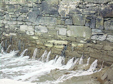 A river runs through the gaps in the pier wall on Cape Clear