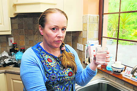 Mary Egan with a glass of cloudy water and, right, her bath, filled recently with tap water.