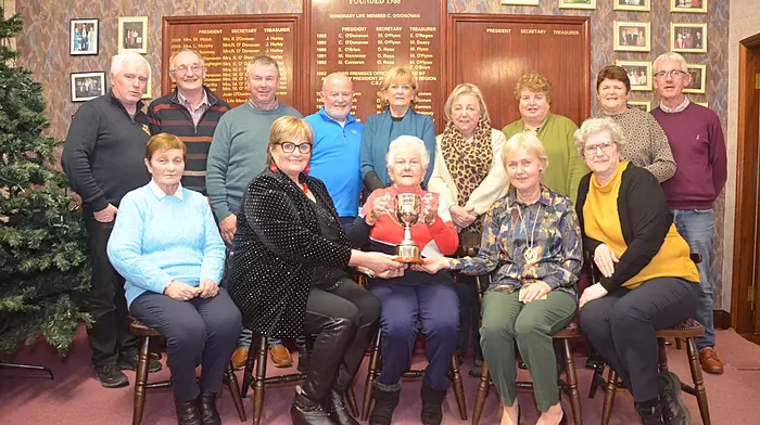 Participants in the bridge club pairs competition were: Front seated, Margaret Shorten, Carmel Murphy winner receiving the Silver Jubilee Perpetual Trophy (presented to the club by Jerry and Margaret O'Flynn) from President Ann Bailey, Jane Ross winner, Kay Russell. Back left Mike Russell, Albert Helen, Pat O'Donoghue, Dermot Lucey, Lucia Murphy, Margaret O'Donovan, Norah O'Neill, Liz McCarthy, Donal Cahalane