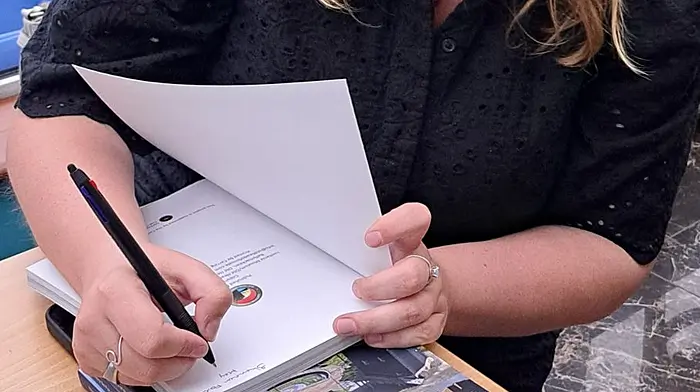 Shannon Forde signing copies of her latest book The Story So Far: 10 Years of the Lusitania Museum and Old Head Signal Tower.    (title of the book in italics)