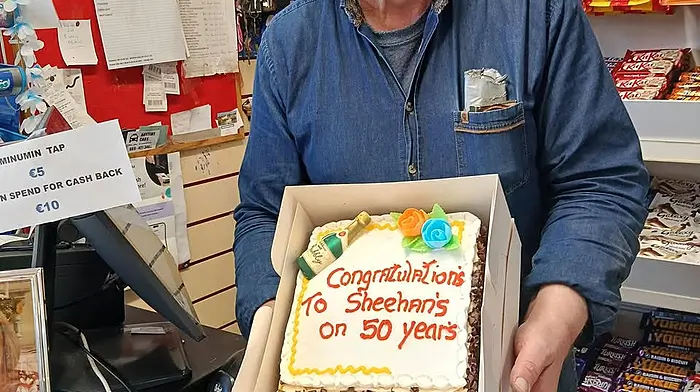 Dermot Sheehan behind the counter of his shop with a celebratory cake to mark the past 50 years of business in Goleen.