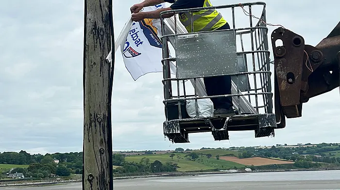 Former crew member of the Courtmacsherry RNLI, Conor Dullea, affixing one of many commemorative Courtmacsherry Lifeboat 200 flags ahead of the weekend celebrations in the village. He was ably assisted by his nephew Niall.  (Photo: Martin Walsh)