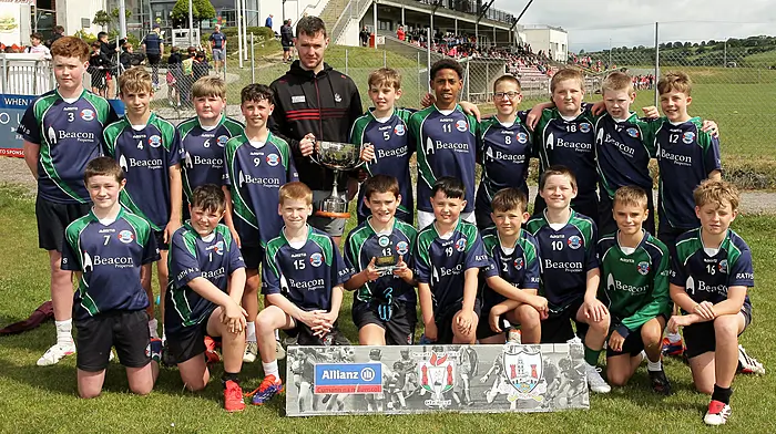 Roinn 3 Boys winners Rath NS receive the trophy from Cork footballer Maurice Shanley.