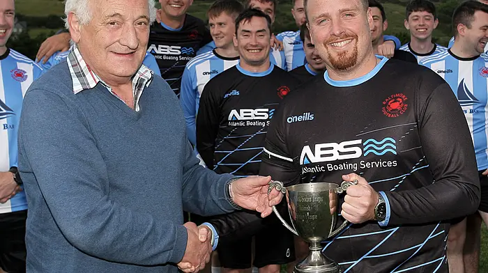 Ronnie Tanner treasurer of the West Cork League presents the trophy to Kieran Lynch captain of the Baltimore FC team that won the O'Brien Water Srvices.com Championship.