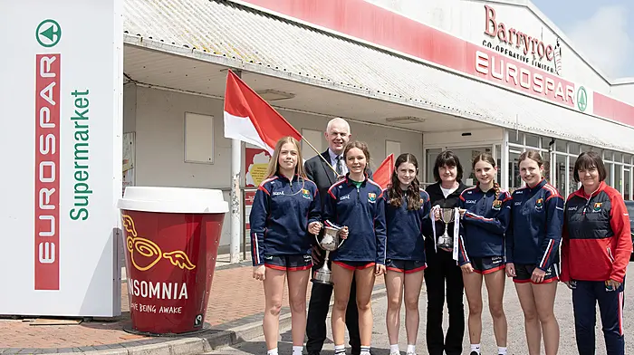 The Ibane members of the Cork team that won the All-Ireland U14 platinum final and their coach Mary Harrington on a visit to the EuroSpar Supermarket Barryroe Co-Op with the Munster and All-Ireland trophies; Kate Collins, John Cuddihy (Eurospar Barryroe), Niamh Doyle, Aoife Harte, Christine Cahalane (Eurospar Barryroe), Aoife Walsh, Aibhlin McCarthy and Mary Harrington. (Photo: Martin Walsh)