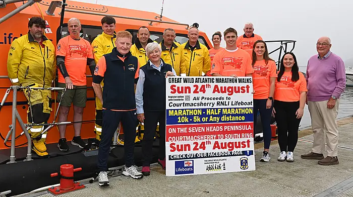 Munster and Ireland rugby star Jack Crowley, who is a familiar visitor to the Courtmacsherry area, launched the 2025 Great Wild Atlantic Marathon Walks in aid of the Courtmacshery RNLI at the weekend.  The organisers wore special electric orange tee shirts which are available at the Courtmacsherry Community Shop.  From left: Ken Cashman, Richard O'Flynn, Taylor Murphy, Vincent O'Donovan, Simon Locke, Angela Veldman, Tadgh McCarthy and Denis Murphy, Aoife Daly, Jack Crowley, Micheál Hurley, Emma O'Donovan, Elaine Kirby and octogenarian Tom McGrath, a granduncle of Jack Crowley, both of whom holiday in Dunworley. The  event that will take place on Sunday August 24th, is the ninth iteration, and has so far raised a sum of €73,012.                                      (Photo: Martin Walsh)