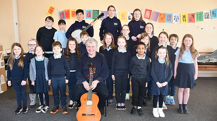 Kilcoe National School were delighted to welcome singer songwriter John Spillane last week, where he and the pupils sang and played music together. Right: Sisters Saoirse and Róisín Hickey who are 1st and senior infant class pupils, pictured with their mum Rachel Hickey and grandparents Justine and Denis Fay. (Photos: Anne Minihane.)