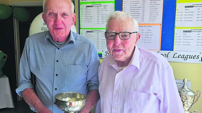 Scoil Phádraig Naofa former pupils Finn Mannix and Paddy Crowley on a recent visit to the school, holding the original School League Cup (1954-1974).