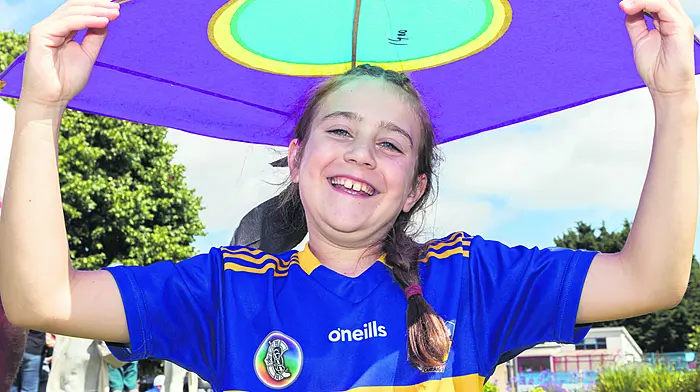 SPEC: Carrigaline, Cork, Ireland. 04th July, 2026. Holly Davis uses her kite to shelter from the sun at the Basant Panchami festival, a traditional  kite flying festival that was celebrated at the local community park in Carrigaline, Co. Cork. - Picture David Creedon