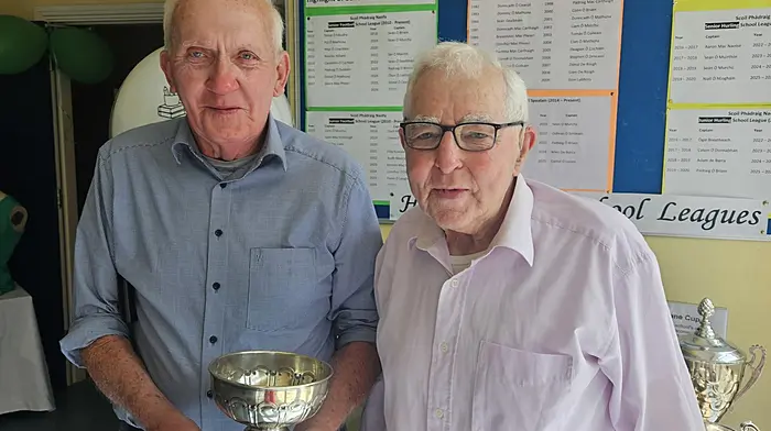 Former pupils of Scoil Phádraig Naofa Finn Mannix and Paddy Crowley on a recent visit to the school, holding the original School League Cup (1954-1974).