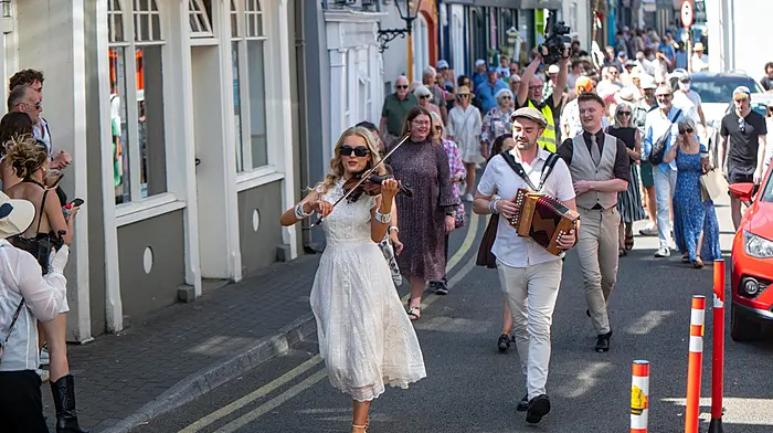 REPRO FREE
Members of An tAthrú, site-responsive street performance, lead the crowd through the small streets of the town during Kinsale Arts Weekend.
Picture. John Allen

Sun, Sea and Storytelling: Kinsale Arts Weekend Celebrates 10th Anniversary This Weekend with Over 50 Spectacular Events

KINSALE, IRELAND – July 2026. With the weather forecast promising a spectacular, sunny weekend ahead, there is no better time to experience world-class culture in one of Ireland’s most beautiful seaside towns. This weekend, from 9th to 12th July 2026, the historic coastal town of Kinsale will transform into a stage for the milestone 10th anniversary of the Kinsale Arts Weekend.

This year’s festival features a packed schedule of over 50 events spanning music, theatre, film, visual art, literature and dance. Over four days, visitors and locals alike are invited to dive into an immersive cultural journey across intimate and unconventional venues throughout the town.

Festival Highlights
GHOSTIS: Celebrating the Origins of Welcome

GHOSTIS: Celebrating the Origins of Welcome, a joyful and thought-provoking live panel discussion curated by artist and writer Jennie Moran, taking place at the Methodist Church in Kinsale on Friday, 10th July at 6pm. This unique event explores the deep customs, rituals and philosophies of hospitality across global cultures through personal stories, food and community. This year’s inspiring contributors include Ali Hamou, a human rights advocate and founder of One Community Cork; Cecilia Gámez Campanella, a founding member of the Mexican Community in Cork who builds cultural bridges through music and art; and Virginia O'Gara, the co-founder of My Goodness and the Cork Urban Soil Project who explores sustainability and the circular economy as acts of care. Together, these speakers will share moving perspectives on how we welcome strangers, share traditions and create a collective sense of home.

An Operatic Masterpiece: The Lament for Art O'Leary

Another extraordinary highlight of the weekend is The Lament for Art O'Leary, taking place on Saturday, 11th July in a powerful collaboration with the Joseph Walsh Studio. This event offers a haunting, contemporary operatic reimagining of one of Ireland's most profound expressions of grief, love and defiance. Featuring an evocative score by composer Irene Buckley and text by poet Vona Groarke, the experience begins with an open-air introduction to the tradition of keening by Professor Tríona Ní Shíocháin, before moving indoors for an atmospheric concert featuring powerhouse sopranos Emma Nash and Kim Sheehan.

Adding to the festival's vibrant celebration of powerful female voices, audiences can also look forward to Rí Rá Mná: Live Podcast and the compelling short film screening Trína Súile. Taking place on Friday, 10th July at 12:30pm at The Post House Café, Rí Rá Mná brings a live recording of the popular UCC Radio podcast to Kinsale. Hosted by Sinéad Moynihan and Susan Brown, the session features a unique gathering of conversation, song and connection with special guest Gilly McArthur - an acclaimed cold-water swim coach, free climber and author - alongside rich harmonic performances by Kinsale’s all-female Sound Waves Choir. Complementing this on Sunday, 12th July at 1:00 PM at the Carmelite Friary, filmmaker Darina Clancy presents Trína Súile, a powerful Irish-language short film project exploring the overlooked legacies and remarkable resilience of historic Irish women. Presented with English translations provided, the screening will be followed by an illuminating discussion on women’s history and storytelling with journalist Clodagh Finn, beautifully blending heritage, language and contemporary reflection.

With beautiful sunshine on the horizon, an incredible line-up of talent and a town bursting with creativity, Kinsale is the ultimate destination this weekend.

To view the complete 2026 programme and secure tickets, please visit www.kinsaleartsweekend.com.

– ENDS –

Media Contact:

Siobhán Howe | 0872029484