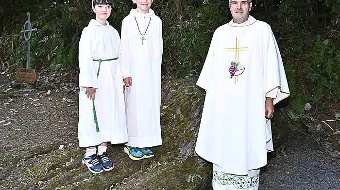 Fr Anthony O'Mahony, Co-PP, with servers Sadhbh Deasy (left) and Clodagh O'Driscoll at the Mass Rock, Béal an Aifrinn, near Broadstrand last Friday evening.  (Photo: Martin Walsh)
