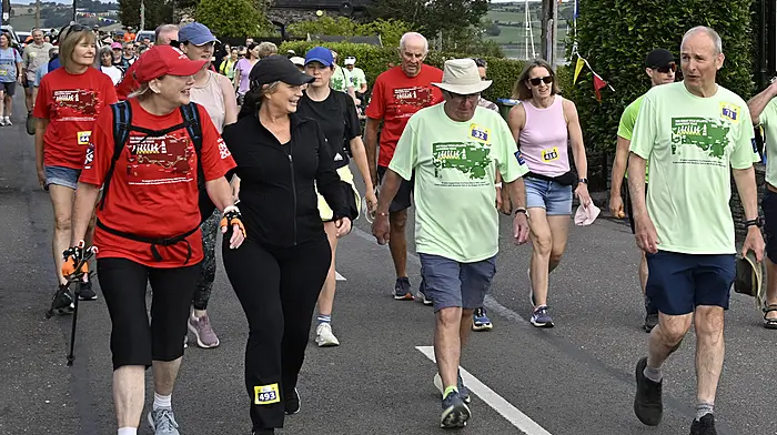 An Taoiseach Micheál Martin (right) engaging with fellow walkers as his friend and local Ray Doherty listens intently while they make their way through Courtmacsherry village on the Courtmacsherry RNLI Great Wild Atlantic Marathon Walks . (Photo: Martin Walsh)