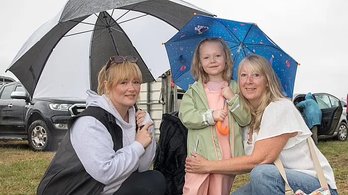 SPEC: FARMING: Bantry, Cork, Ireland. 30th August, 2026.  Stephanie Coleman, Allie Lynch and Maureen Harmon staying dry under the umbrellas at the annual agricultural show that was held in Bantry, Co. Cork.- Picture: David Creedon