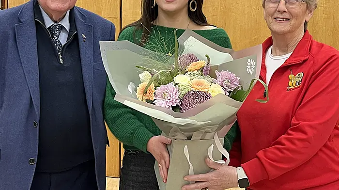 Barry Cogan, Cathaoirleach Comhaltas na Dúglaise, presenting a bouquet of flowers to Ríona Hely, concertina teacher, who was the recent winner of the Seán Ó Riada Bonn óir competition. Branch president Aislinn Cogan is also included in the photo.