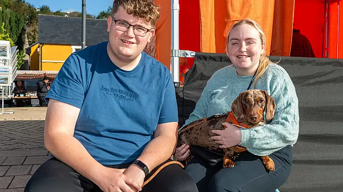 Bantry, West Cork, Ireland. 16th Oct, 2026. The sun shone in Bantry today, bringing locals out to the Friday Market in force. Enjoying the sunshine with 'Frank' the Daschund were Peter McConn and Karen Gillooly from Bantry. Picture: Andy Gibson.