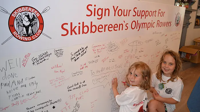 Millie and Lara Dempsey signing their names on the huge poster at the pop-up shop. (Photo: Anne Minihane)