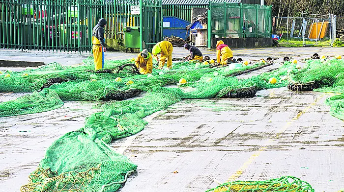 the calm after Storm Eunice, as fishermen mend their nets the following morning on Keelbeg Pier. 		 (Photo: Andrew Harris)